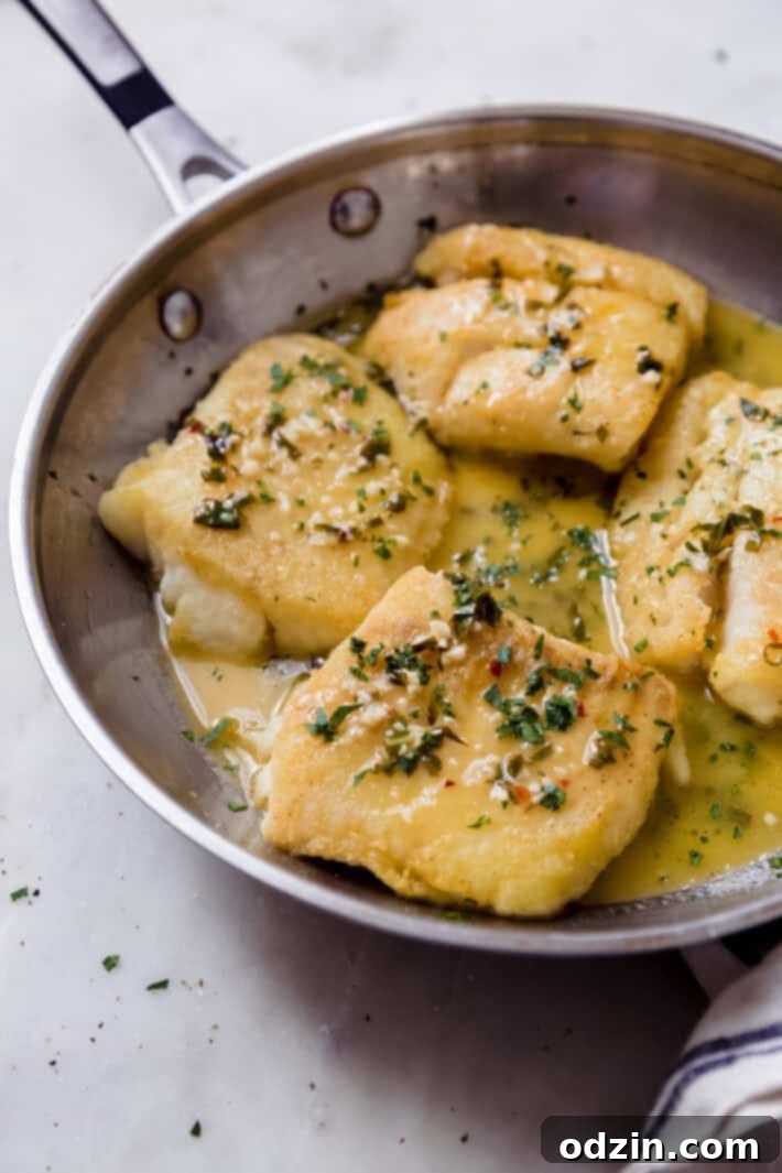 The Ultimate Pan-Fried Fish with Fresh Basil and Zesty Lemon Butter 2 stainless steel skillet with pan-fried fish topped with lemon butter