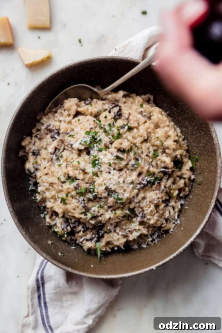 hand cracking pepper in mill over bowl of risotto