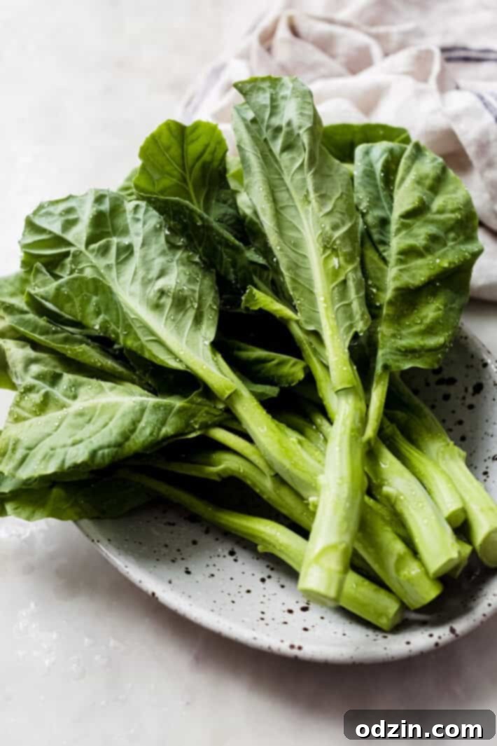 Vibrant green stalks of fresh Chinese broccoli (Gai Lan) on a speckled plate, ready for preparation.