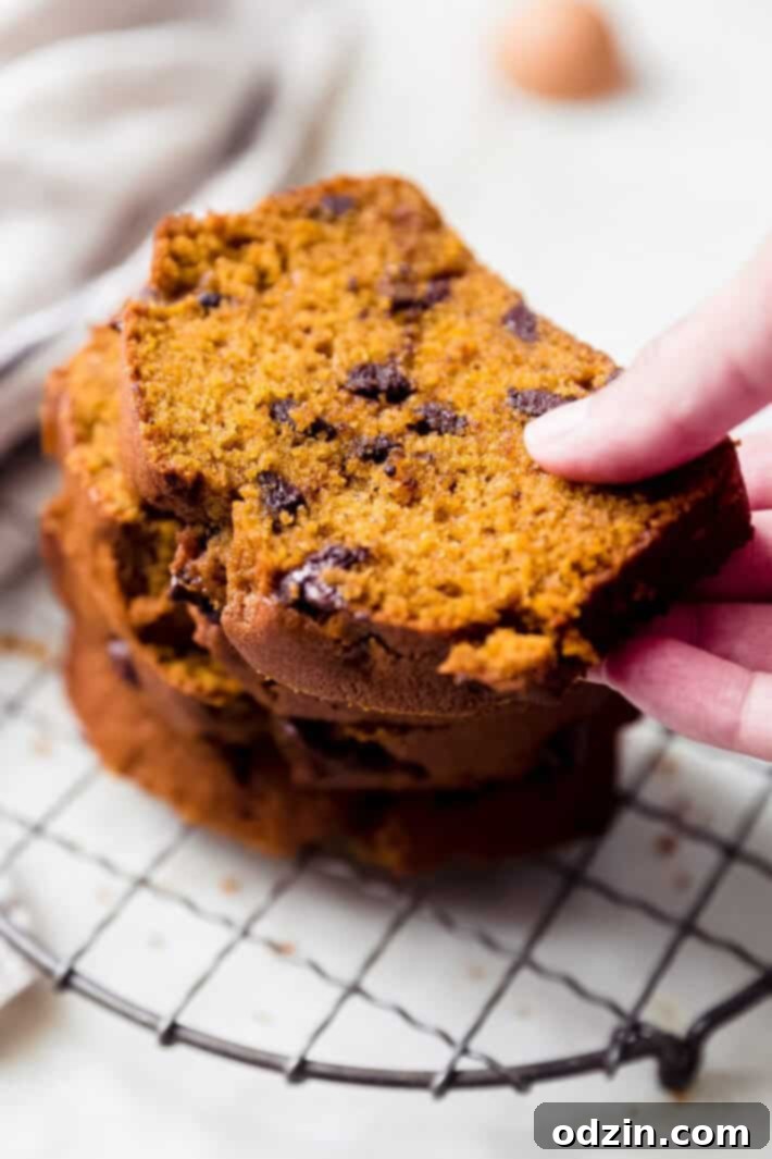 hand lifting slice of pumpkin loaf from wire trivet
