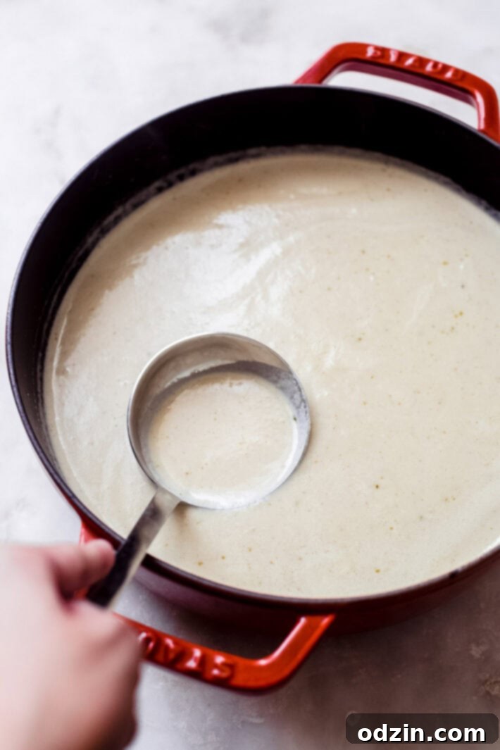Velvet Truffle Cauliflower Dream 6 A Dutch oven filled with freshly pureed roasted cauliflower soup, with a ladle resting inside, ready to be served.
