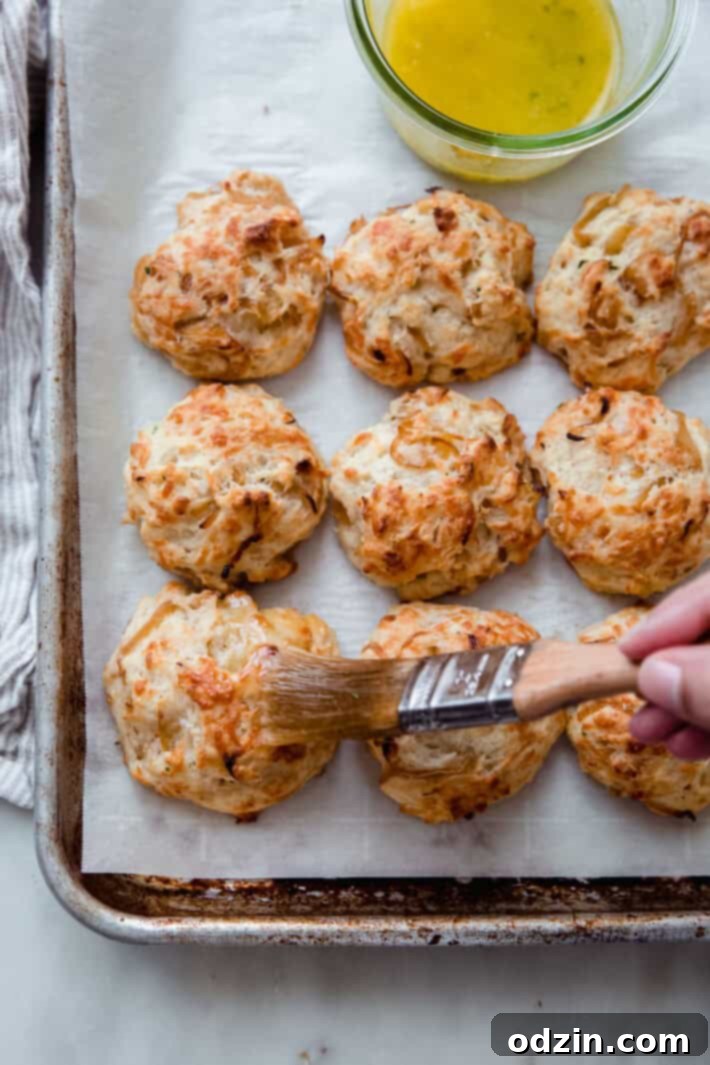 Hot, freshly baked drop biscuits being brushed with melted parsley butter