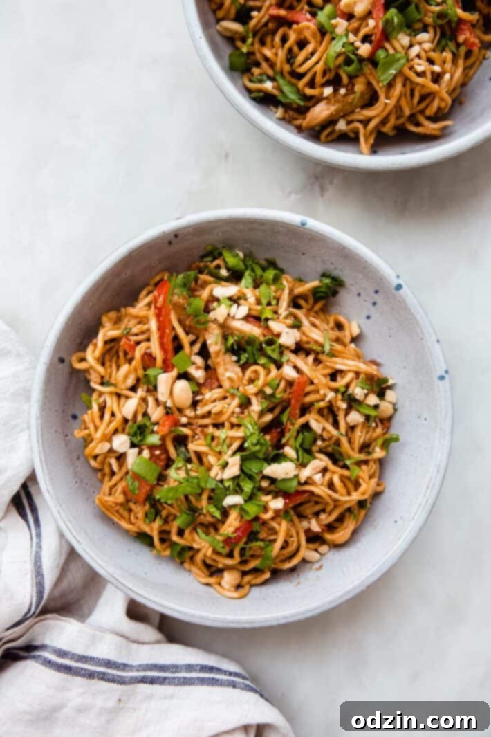 bowls of peanut noodles on white marble with linen cloth