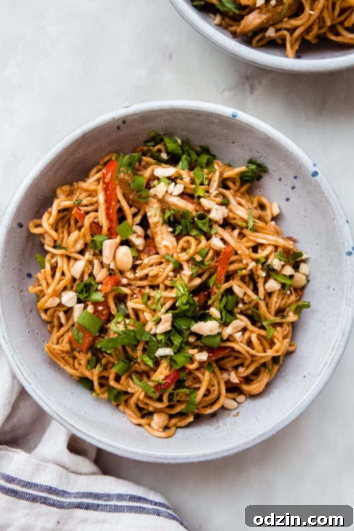 close up of bowl with sesame peanut noodles on white marble