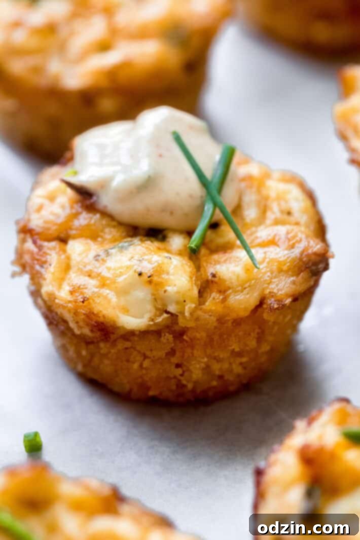 close up of crab cake bite on parchment with chives and sauce on top