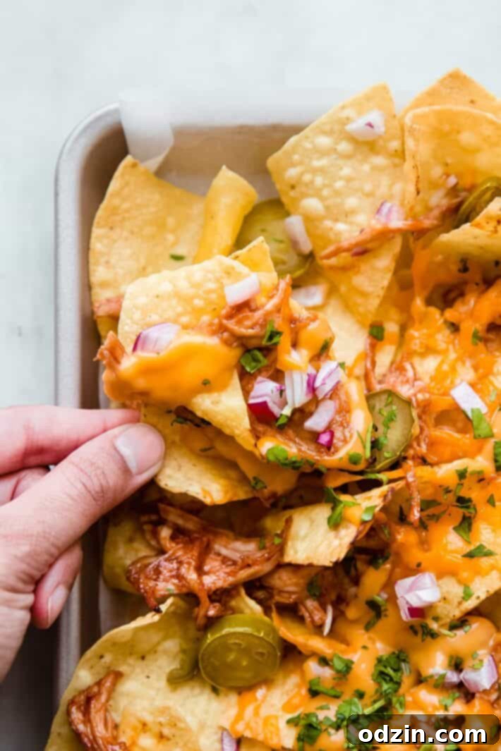 close up of tortilla chip with shredded bbq chicken and toppings
