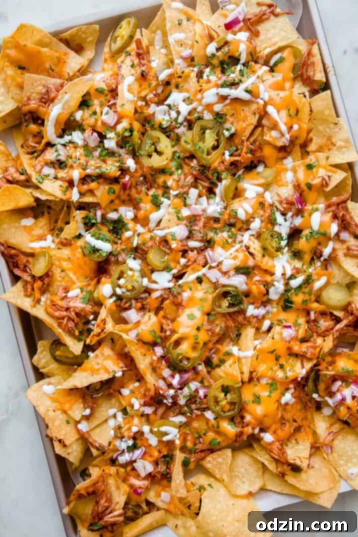 sheet pan with prepared nachos drizzled in sour cream