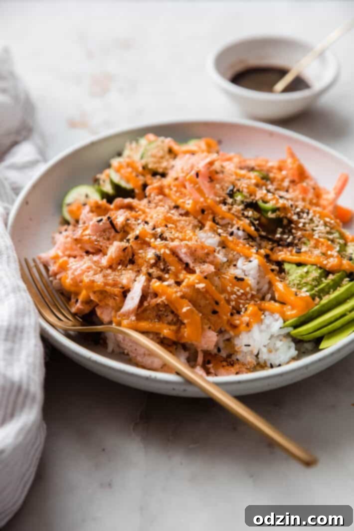 Your Go-To Weeknight Salmon Sushi Bowls 3 side shot of flaked salmon over rice topped with toppings and sriracha mayo