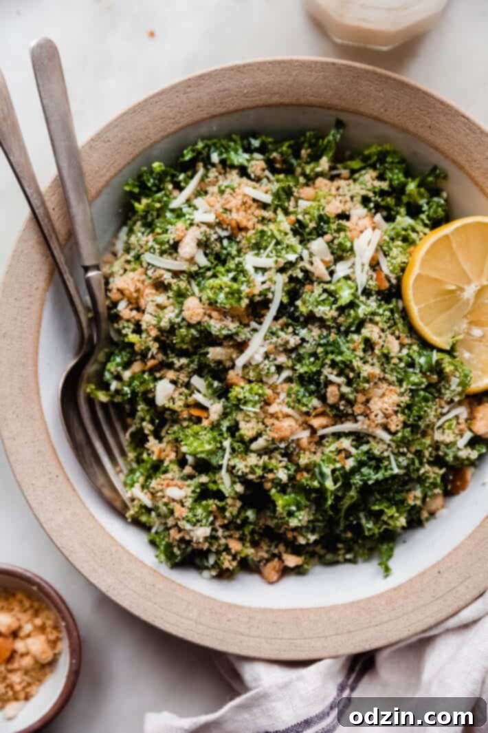 rimmed deep bowl with shredded kale Caesar salad topped with toasted parmesan bread crumbs