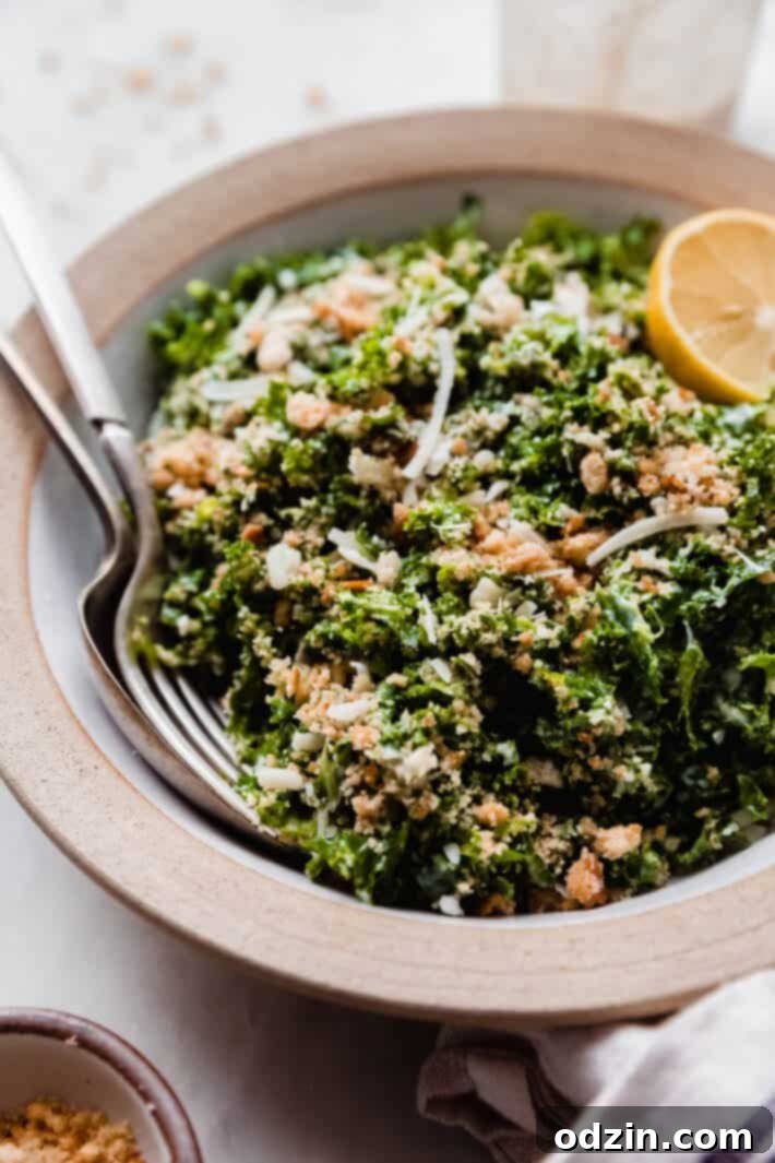 spoon and fork resting in salad bowl showing crunchy bread topping on kale