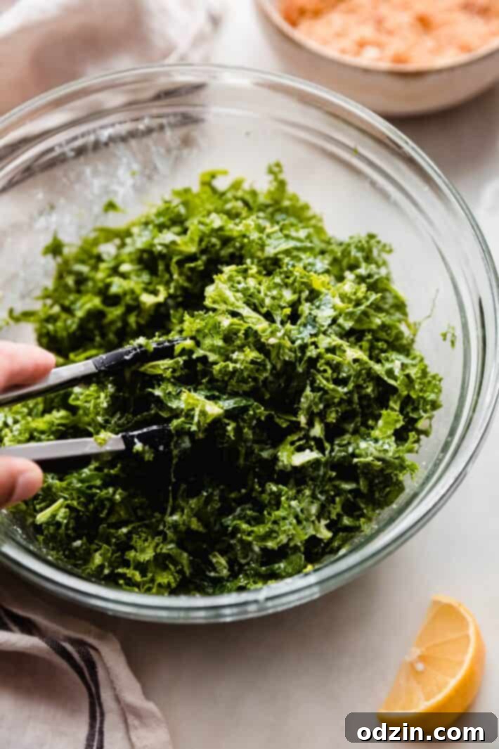 shredded kale tossed with yogurt caesar dressing in glass bowl