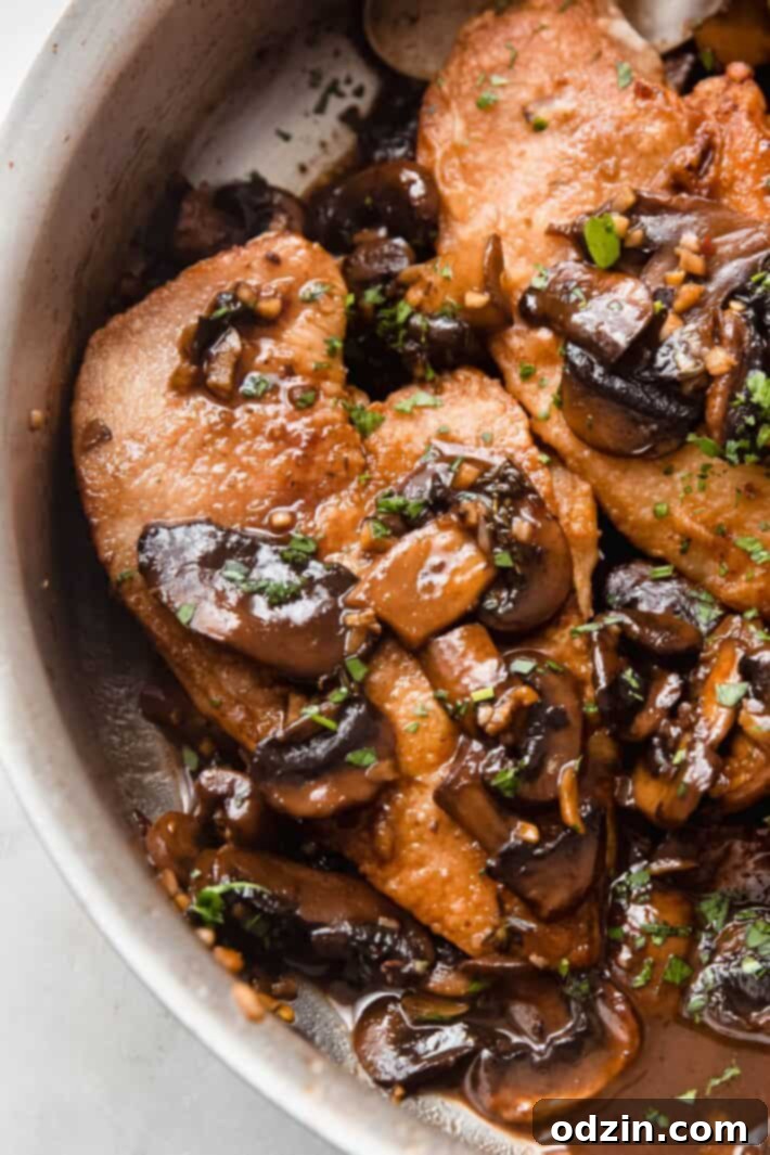 Close-up of golden seared chicken topped with rich balsamic mushrooms and fresh parsley