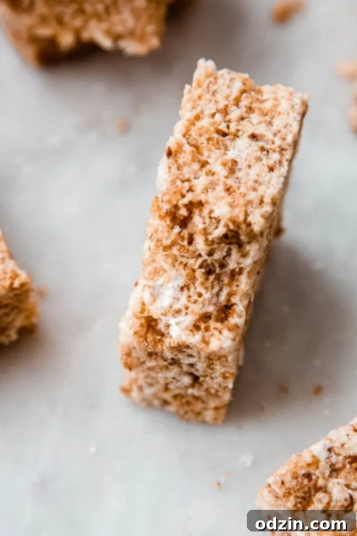 Golden Brown Butter Toasted Marshmallow Krispie Treats 3 Bitten Rice Krispies Treat on a white marble surface, highlighting its soft, chewy interior.