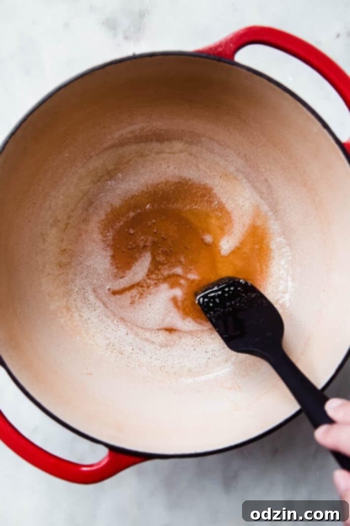 Golden Brown Butter Toasted Marshmallow Krispie Treats 6 Browned butter shimmering in a cast iron pan, with a spatula showing the golden color.