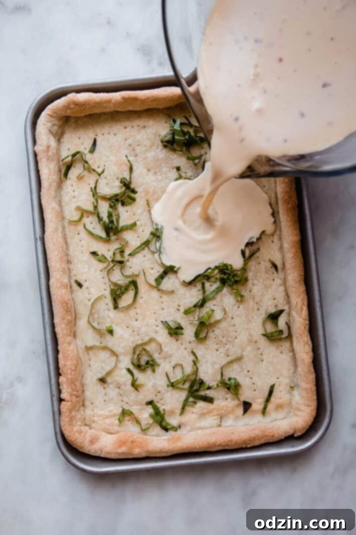 Pouring the egg and cream custard into the par-baked quiche shell, ready for tomatoes and basil.
