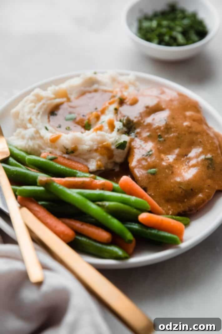 A complete meal of chicken with gravy, mashed potatoes, and green beans on a cozy setting