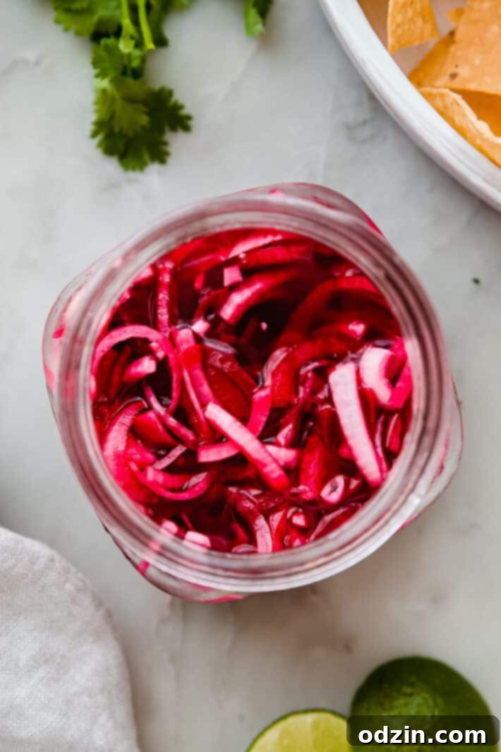 A close-up of quick pickled onions in a jar, showcasing their beautiful pink color and submerged state