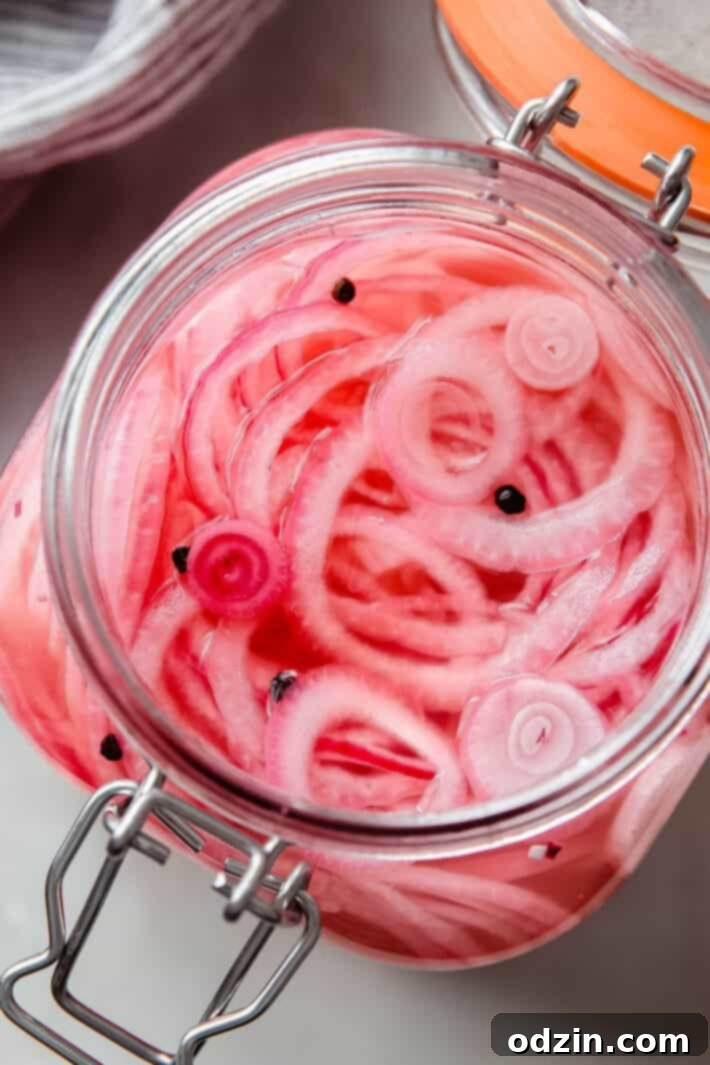 Jar with pickled onions and black peppercorns, ready to be stored
