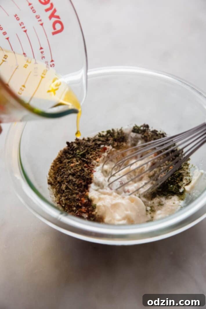 oil pouring into dressing bowl with whisk