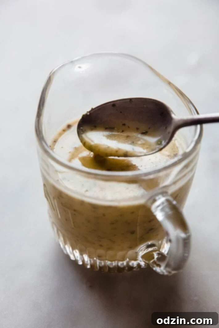 spoon lifting dressing from glass cup