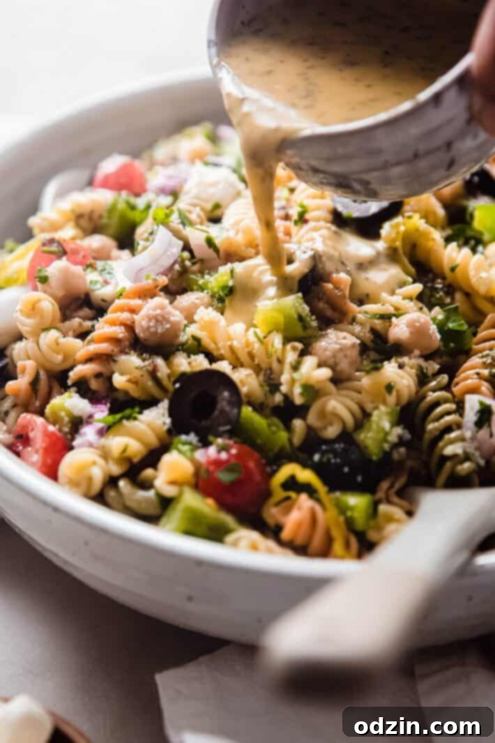 Crowd-Pleasing Zesty Italian Pasta Salad 6 pouring dressin on pasta salad