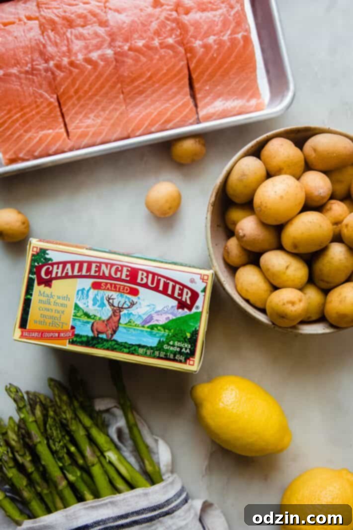 salmon, potatoes, asparagus, lemons' and challenge butter on white marble