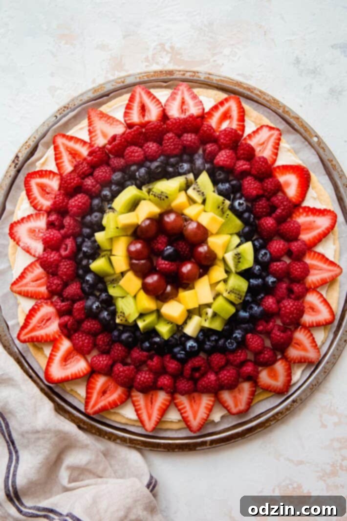 fruit pizza topped with cream cheese icing and fresh fruit