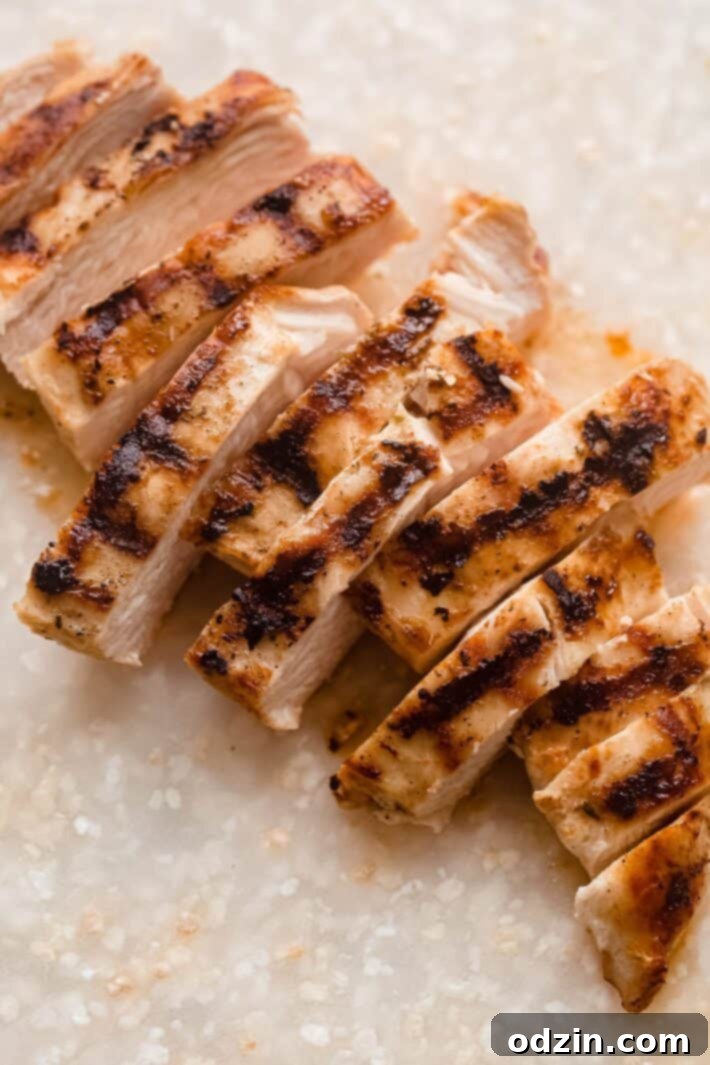close-up of perfectly grilled chicken on a speckled white cutting board