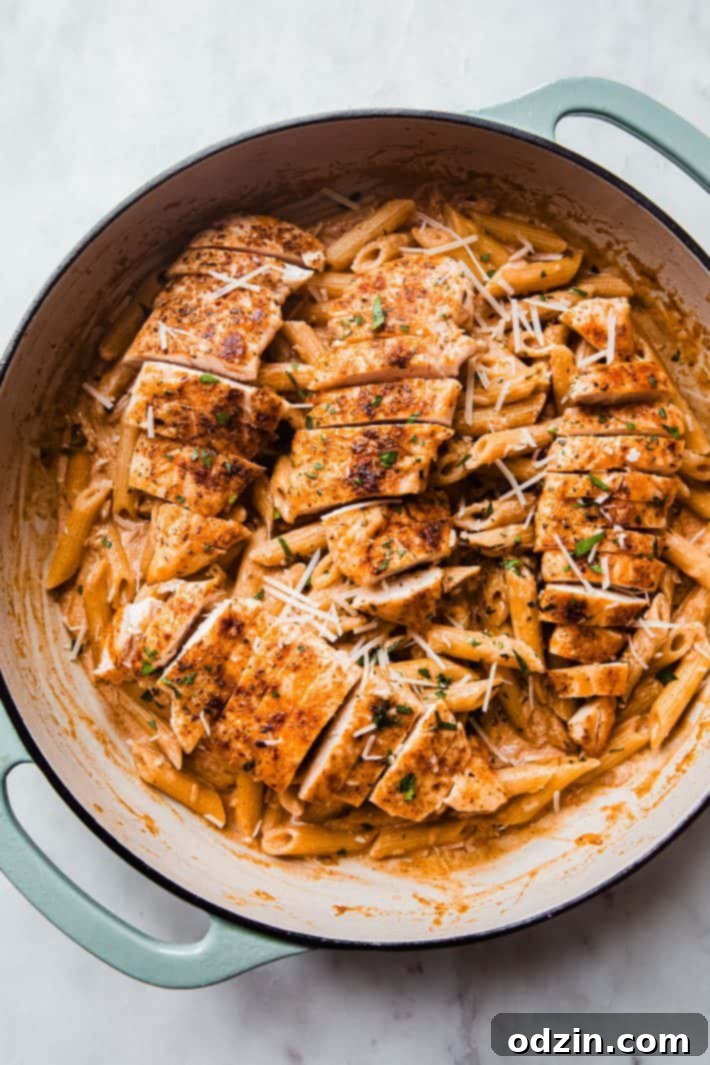 Seared chicken slices on top of creamy pasta, garnished with parmesan and parsley