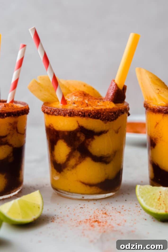 Layered Mangonada with lime wedges on white marble surface