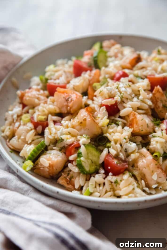 Riviera Prawn & Orzo Bowl 3 Overhead shot of Mediterranean shrimp orzo salad in a speckled bowl on white marble