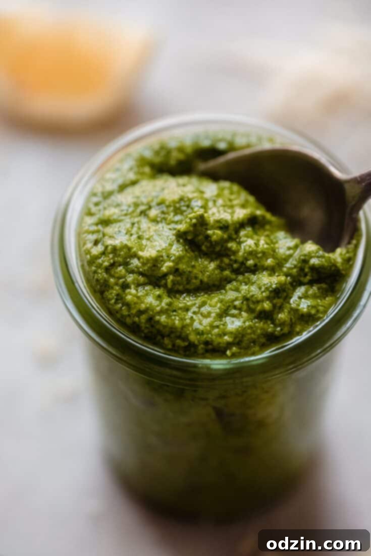 A bowl of Quick Walnut Spinach Pesto, freshly made and ready to be served, garnished with fresh spinach leaves and walnut pieces.