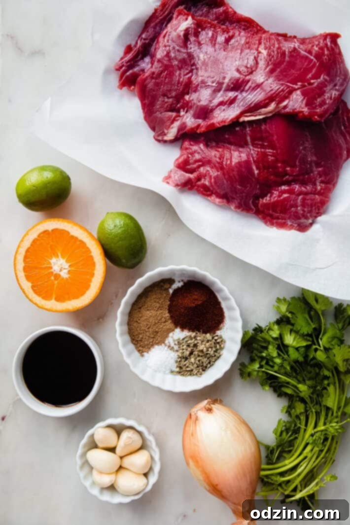 A collection of fresh ingredients for carne asada marinade arranged neatly on a white marble surface, including limes, oranges, garlic, cilantro, and various spices.