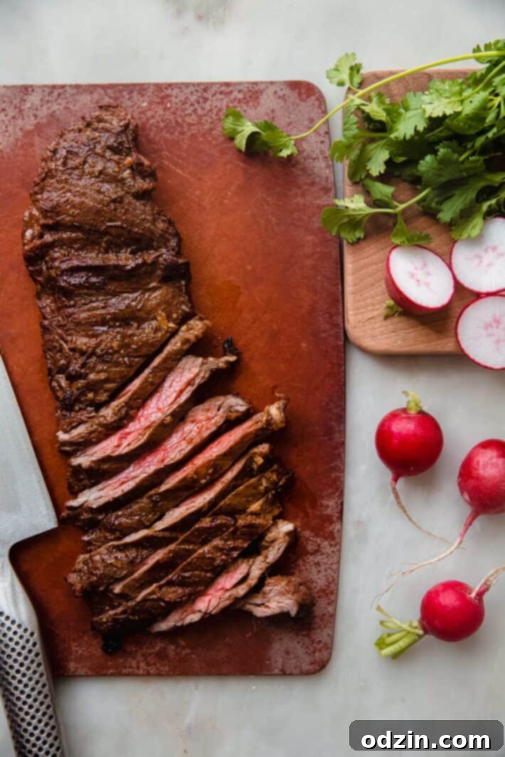 Perfectly sliced carne asada steak arranged on a wooden cutting board, showcasing its tender texture and juicy interior after resting.