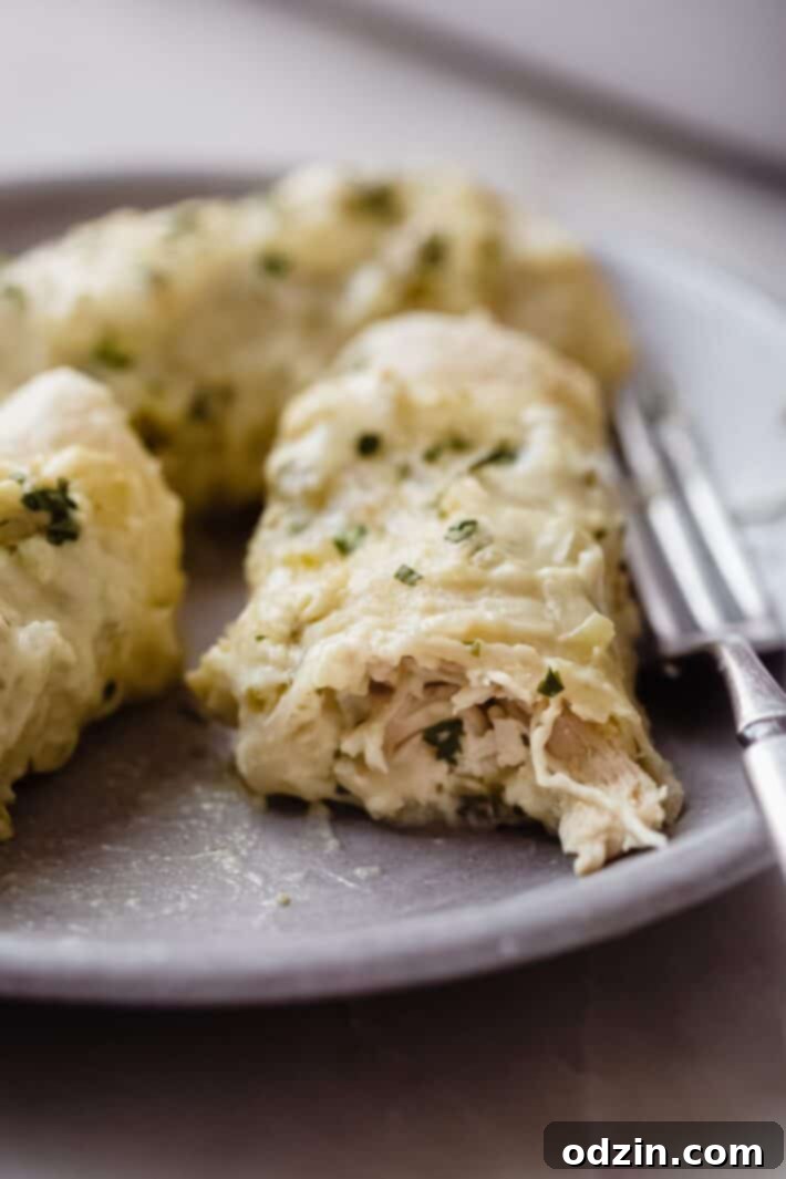 Creamy Salsa Verde Enchiladas 3 halved enchilada on plate with fork