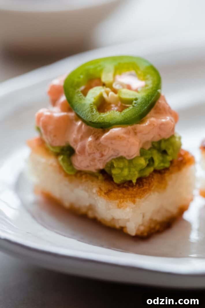 Spicy Salmon Crispy Rice Bites 7 crispy rice with wasabi avocado, spicy salmon, and jalapeno on plate