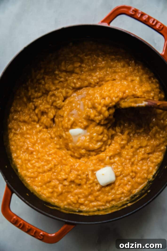 squash risotto in cast iron pot with butter being stirred in