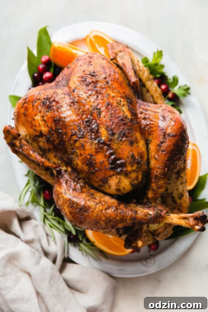 whole roasted turkey on serving platter with rosemary, oranges, and fresh cranberries