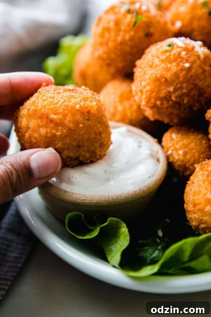 hand holding mashed potato ball and dipping in dip