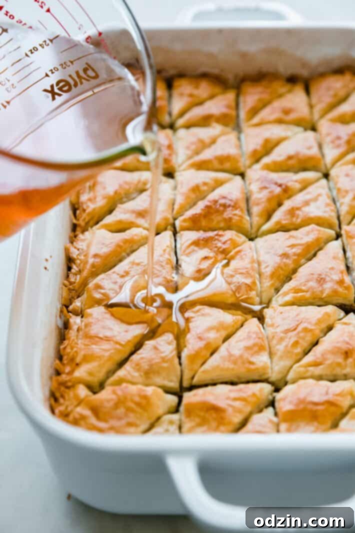 pouring simple syrup over baklava triangles
