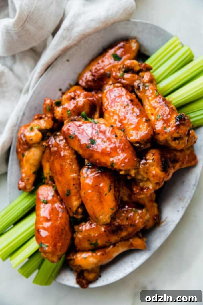 Close-up of crispy firecracker chicken wings on a plate, garnished with green onions.