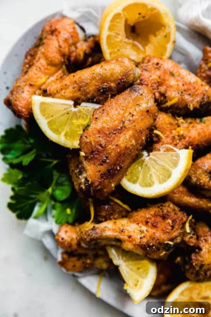 Platter of golden crispy lemon pepper wings garnished with fresh lemon slices and parsley, ready to be served.