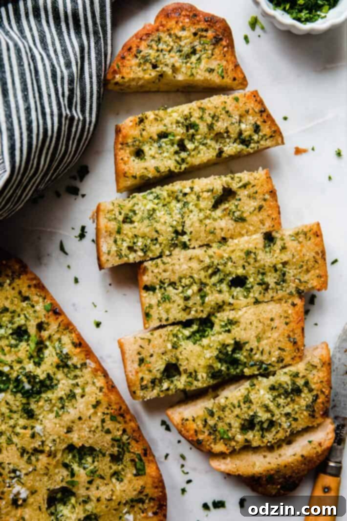 The Ultimate Garlic Bread 7 Beautifully baked garlic bread on white marble, with a tea towel and knife