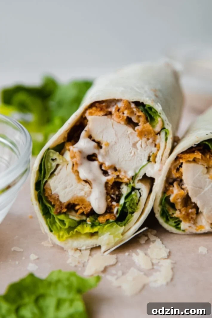 Caesar Crunch Chicken Wraps 2 Sliced crunchy chicken caesar wrap with creamy dressing oozing out, showcasing crispy chicken, fresh romaine, and shaved parmesan.
