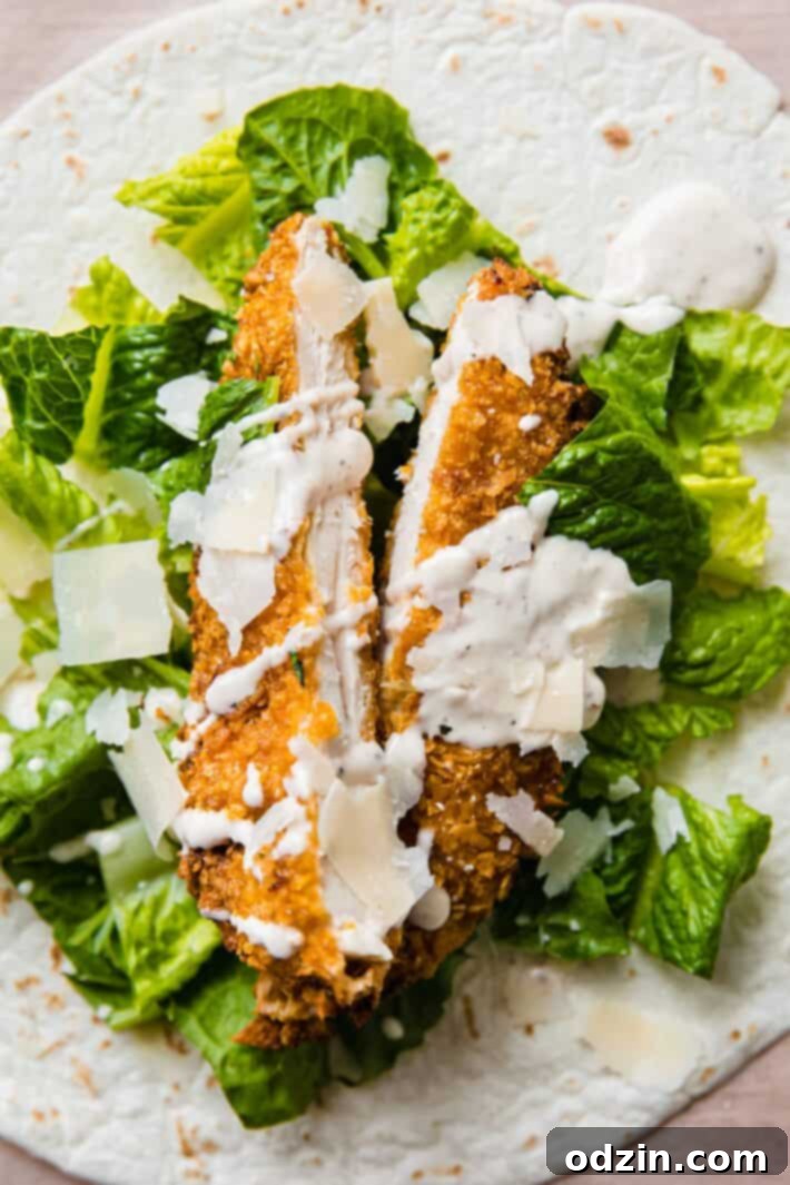 Caesar Crunch Chicken Wraps 5 Close-up of an open chicken caesar wrap, showcasing a crispy chicken tender, shaved parmesan, fresh lettuce, and creamy dressing perfectly layered inside.