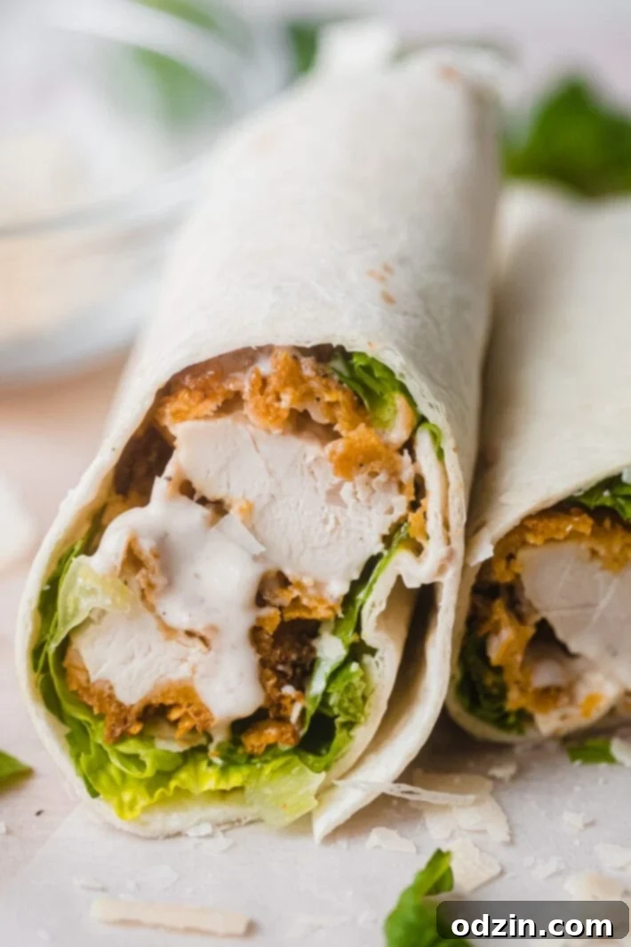Caesar Crunch Chicken Wraps 6 Sliced crunchy chicken caesar wrap on parchment paper, showing the golden-brown chicken and fresh ingredients inside.
