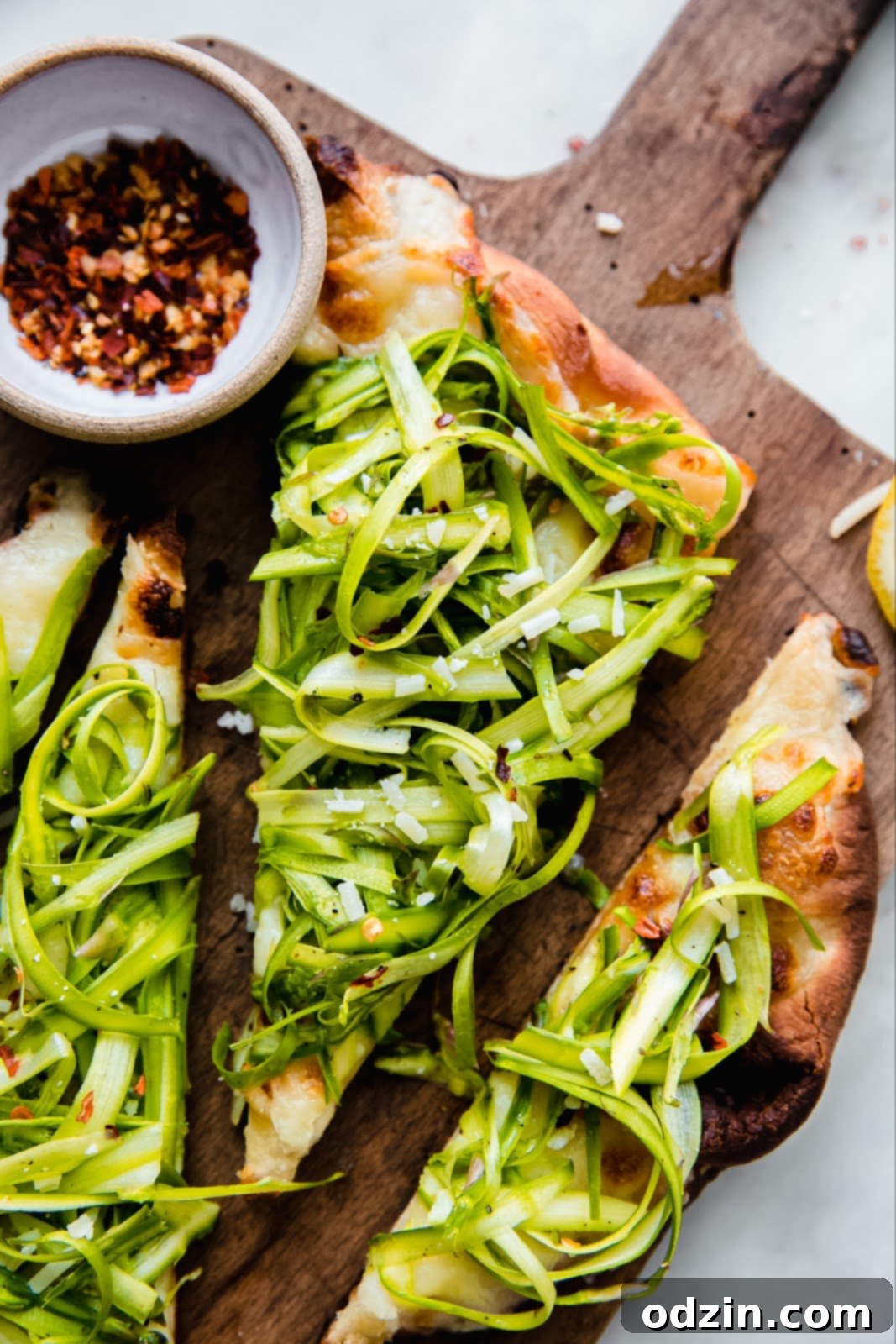 shaved asparagus on flatbread pizza topped with parmesan