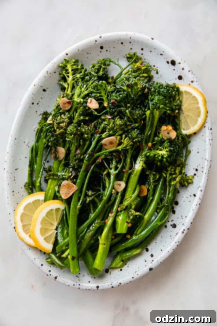 Beautifully plated sautéed broccolini adorned with crispy garlic chips and bright lemon wedges, ready to serve.