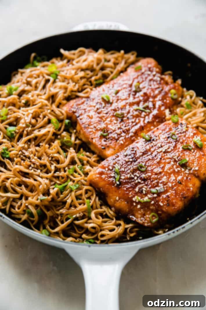 Sticky Teriyaki Salmon with Ginger Noodles 3 Close-up of Teriyaki Sesame Salmon and ginger noodles in a cast iron pan, showing the rich colors and textures of the dish.