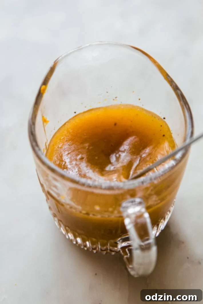 Vibrant Beet Salad with Zesty Citrus Vinaigrette 3 Close-up of vibrant orange citrus vinaigrette in a clear glass measuring cup, ready to be drizzled